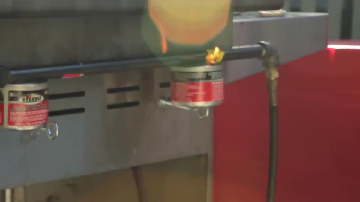 Sterno canister being placed beneath a burn bar on set