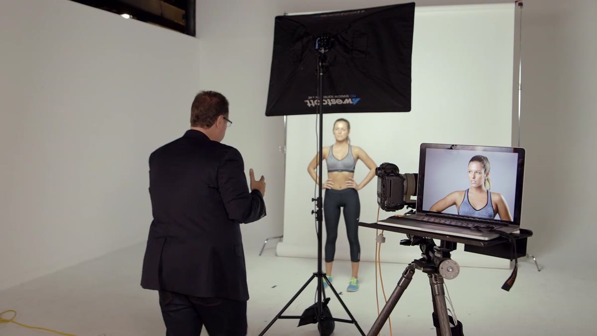 Photographer standing beneath raised softbox, shooting through gap