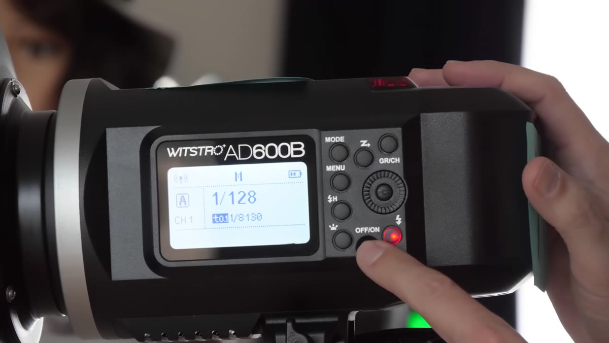Hand holding down power button on AD600 strobe