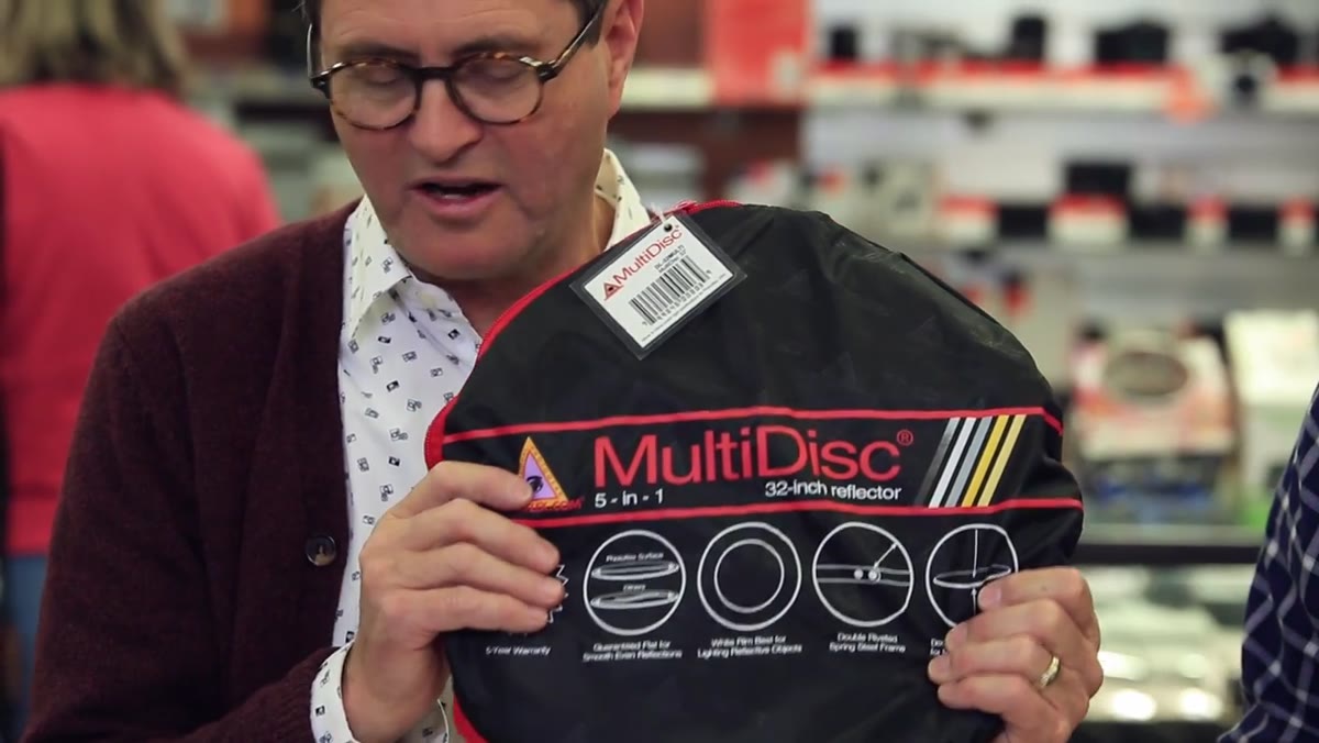 Host holding a Photoflex 5-in-1 reflector with a Matthews stand