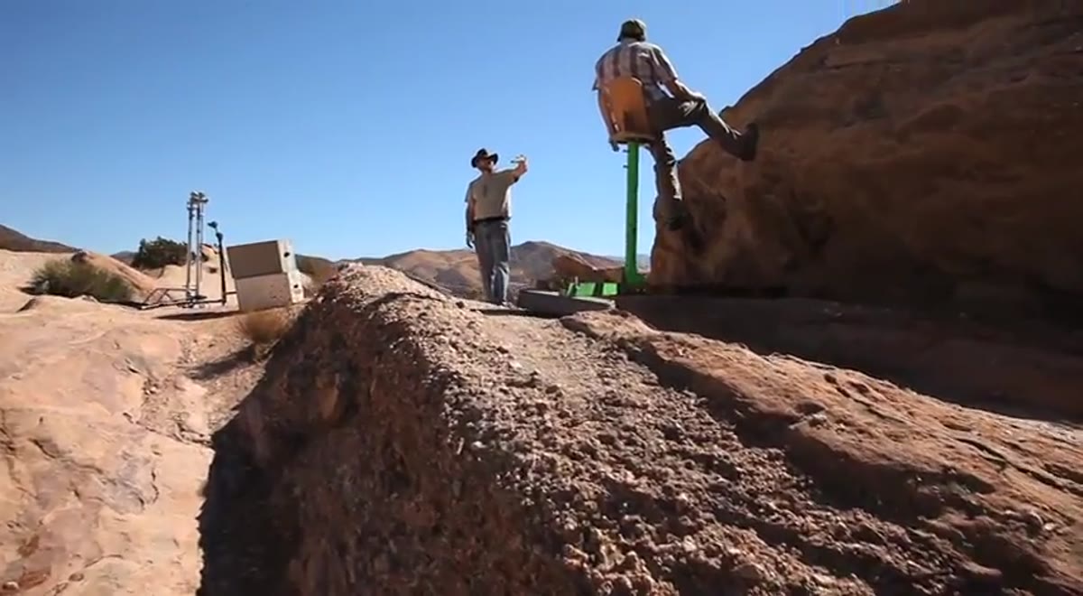 Crew constructing elevated platform structure on rocks