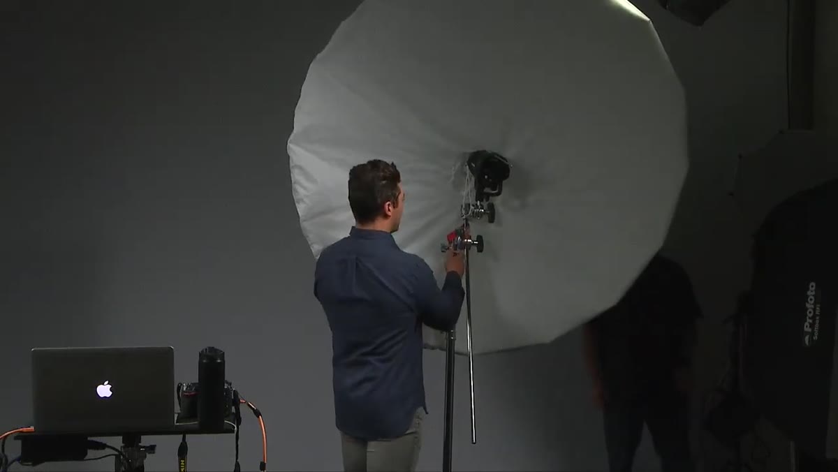 Instructor raising and tilting the umbrella downward on a C-stand