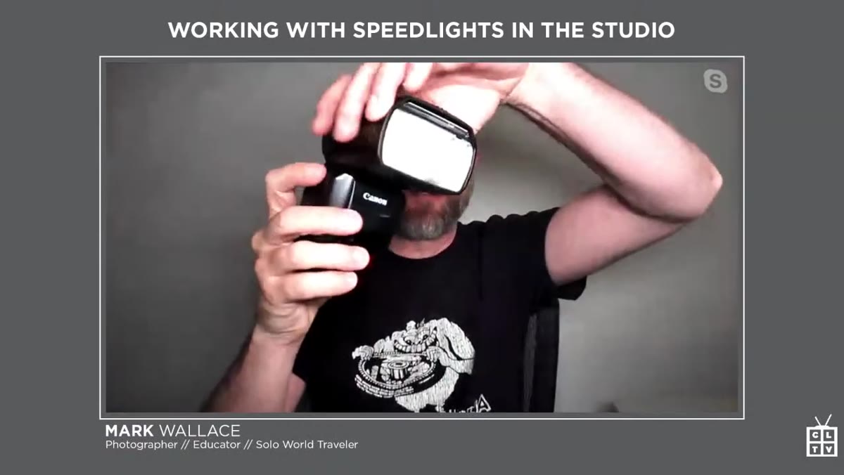 Mark holding a speedlight mounted on a camera body