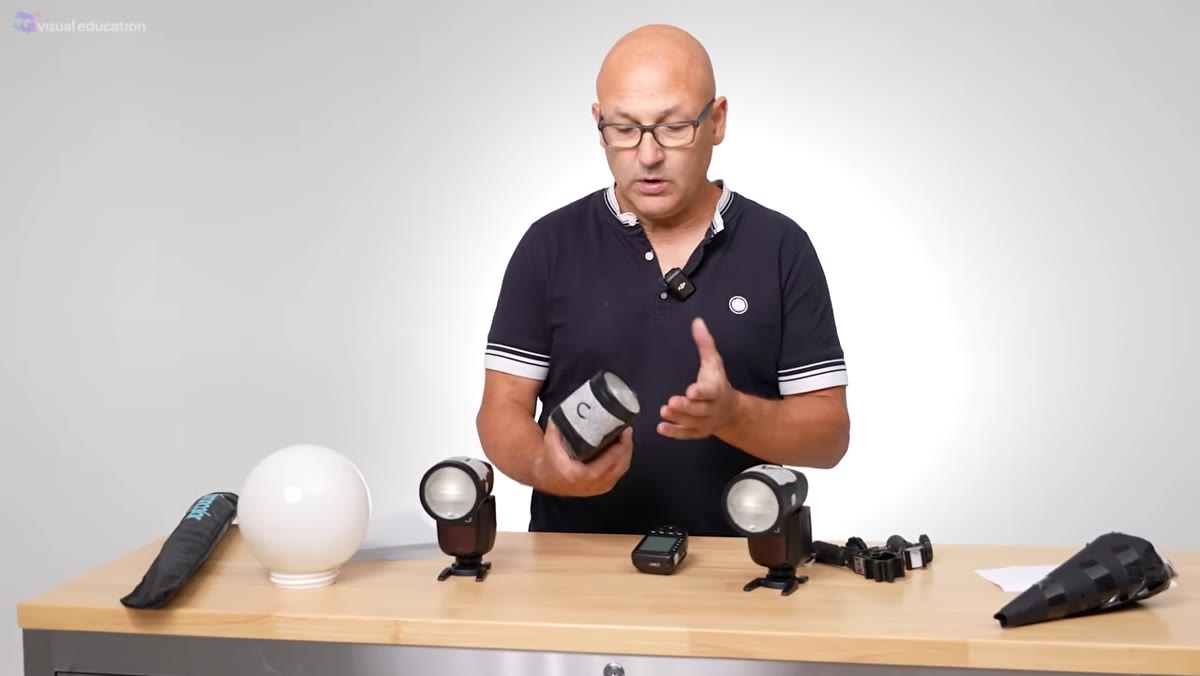 Presenter holding a single speedlight, explaining its basic anatomy