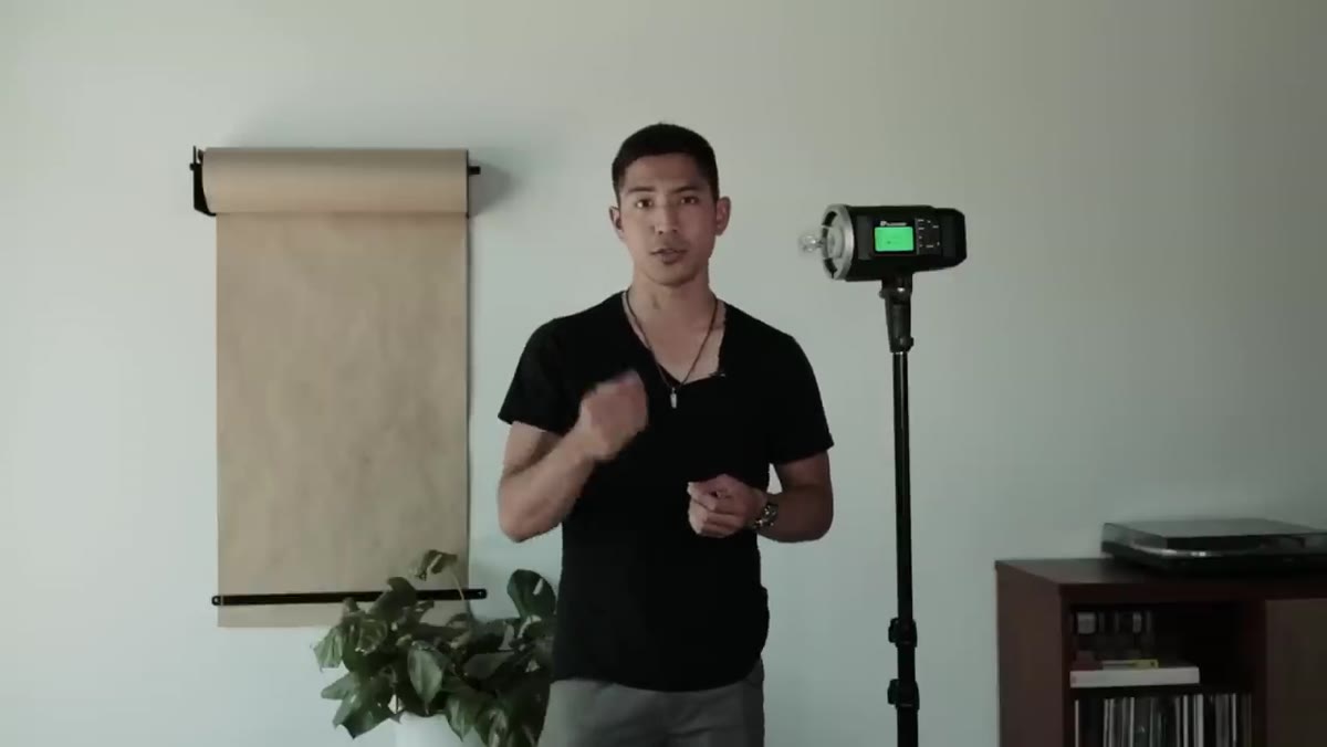 Photographer gesturing toward a single studio flash unit