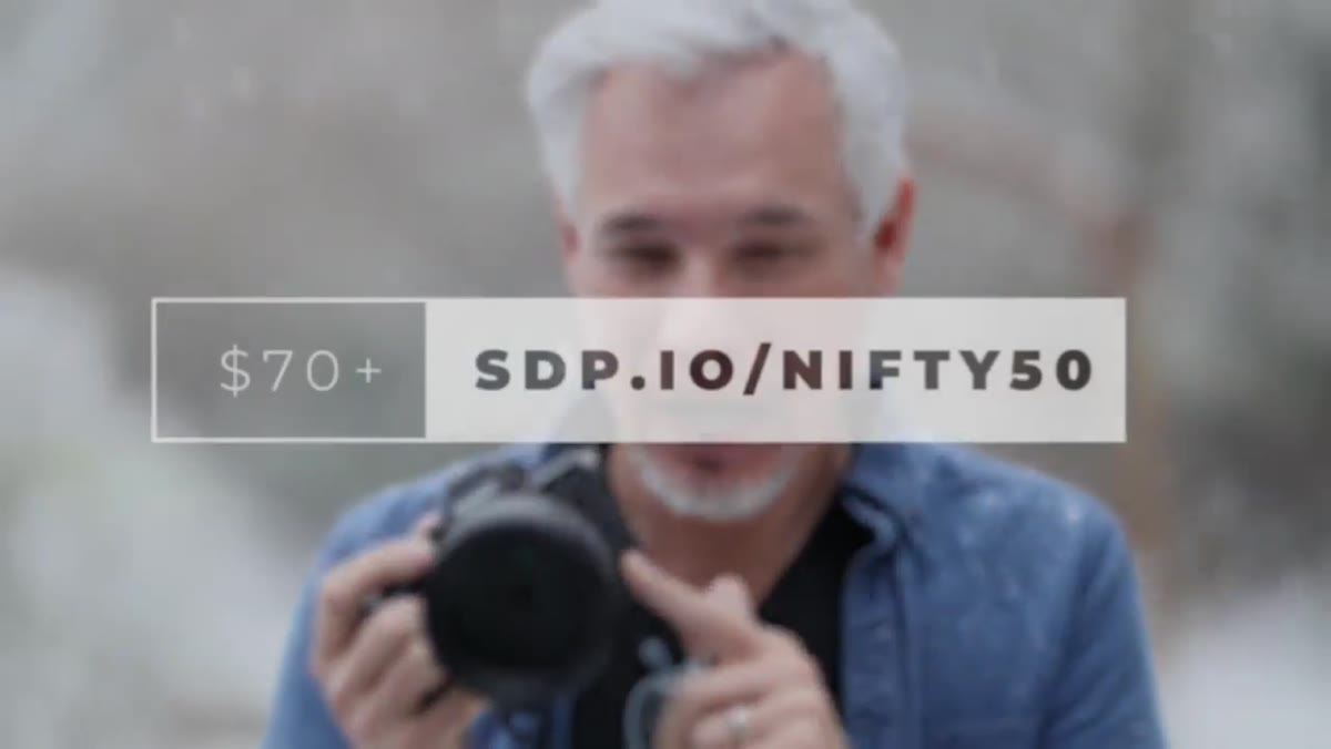 Tony holding or referencing a prime lens with bokeh