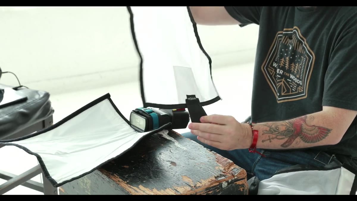 Host attaching the velcro diffuser panel to the front of the bent Flashbender