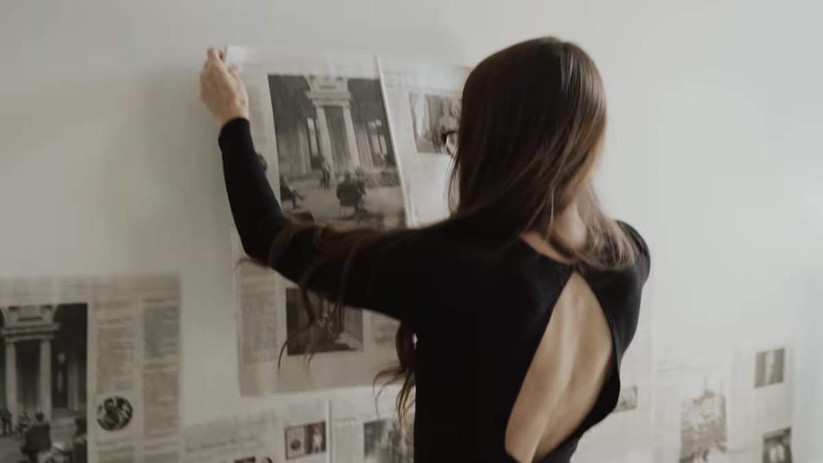 Wide shot of newspaper being taped across wall