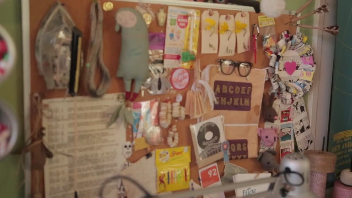 Bulletin board covered with projects, images, and vintage references above desk