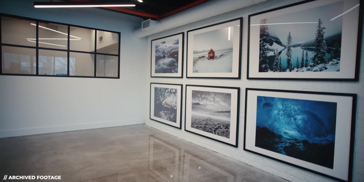 Peter gesturing toward a wall covered floor-to-ceiling with prints